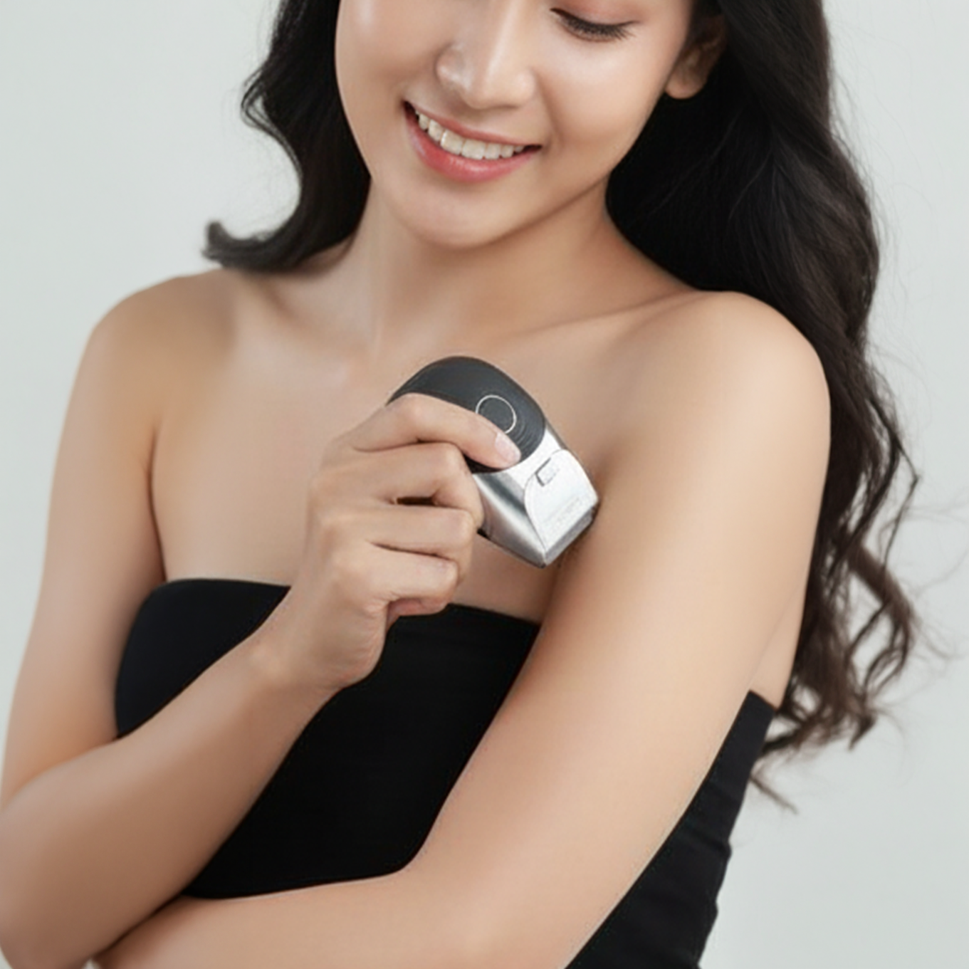 Woman using an electronic device on her arm against a plain background