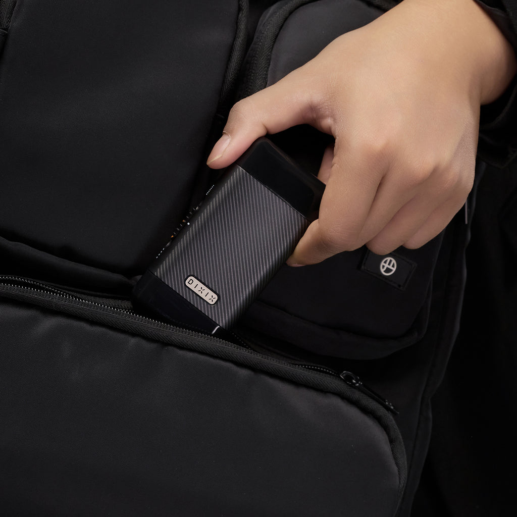 Person placing a black power bank into a black backpack